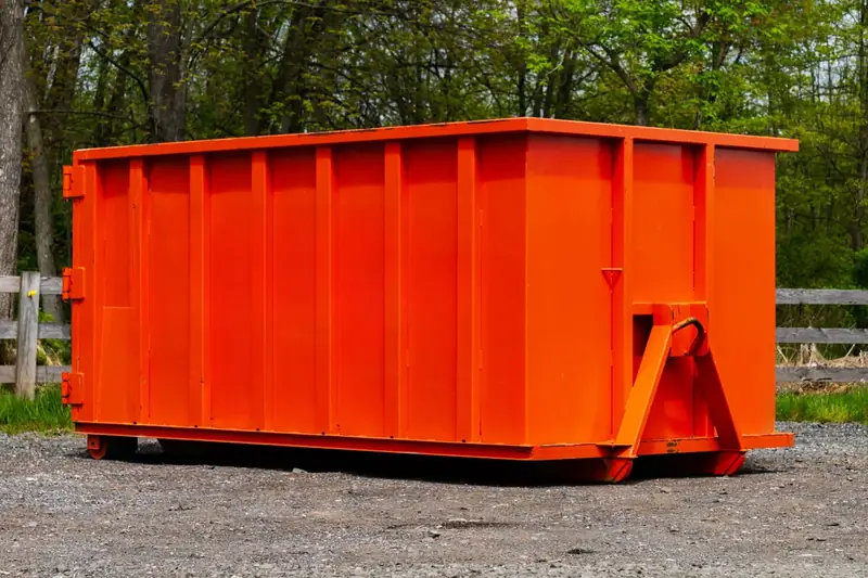 Small roll-off dumpster on a gravel lot, the size class of a 10-yard